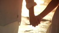 Couple-walking-holding-hands-on-beach
