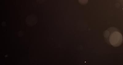 Bright golden particles glowing and floating on dark background in 4K ...