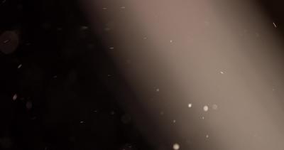 Soft particles floating through raylight in dark background in 4K ...