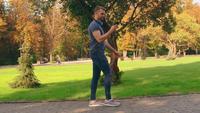 A Guy Walks in A City Park Looking at His Phone