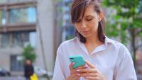 Smiling Woman Holding a Smartphone with An Urban Background