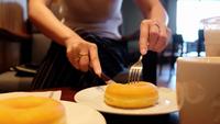 Mains de femme coupant un beignet.