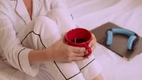 Femme en pyjama blanc apprécie le café au lit