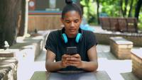 Portrait d&#39;un mec branché assis dans un parc et textos