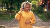 Heureux étudiant dans des écouteurs, écouter de la musique à l&#39;extérieur