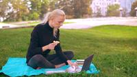 Caucasian girl eating sandwich tout en travaillant à l&#39;extérieur