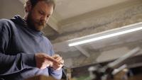 Man Grinds a Piece of Wood with Sandpaper