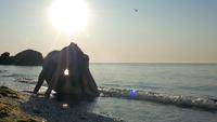 Chica en mono haciendo yoga junto al mar